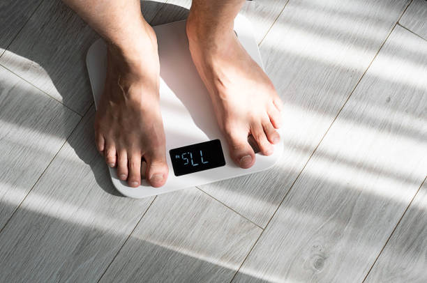 Boy legs stepping on floor scales at home. Weight control concept.
